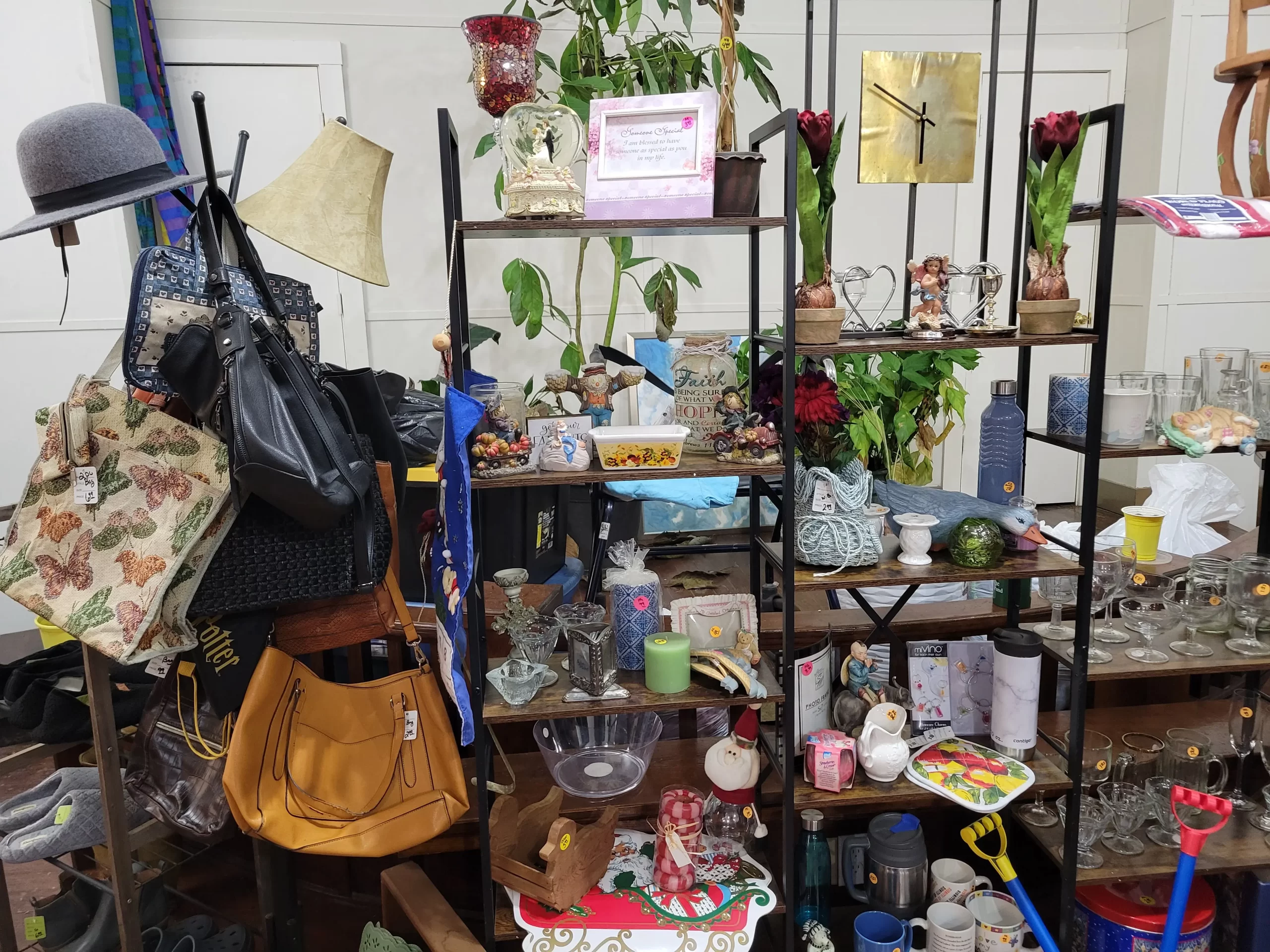 A shelf featuring home goods for sale, such as a clock, a basket, and a selection of purses